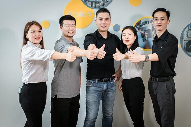 five employees giving thumbs up