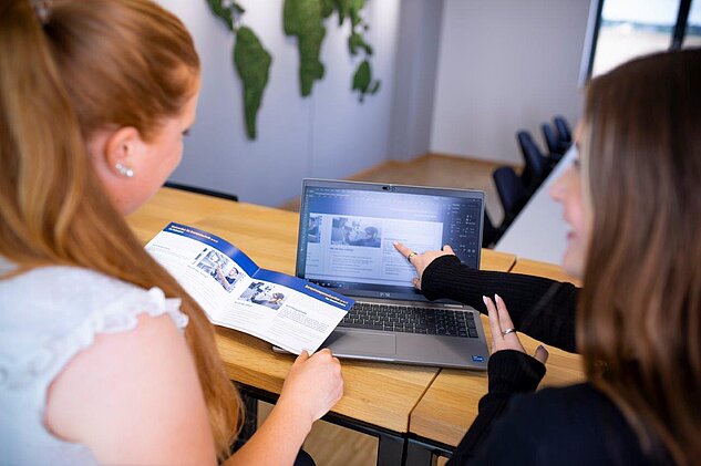 Marketing Apprentice presenting a brochure to her trainer