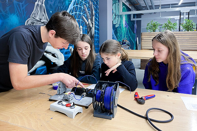 One apprentice teaching three girls on a pneumatic station