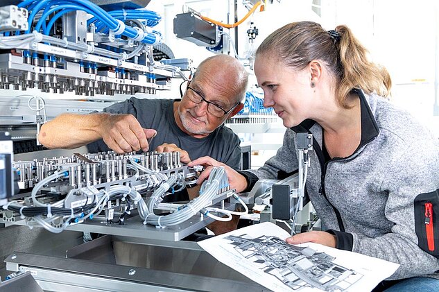 trainer explaining something to a female apprentice in assembly