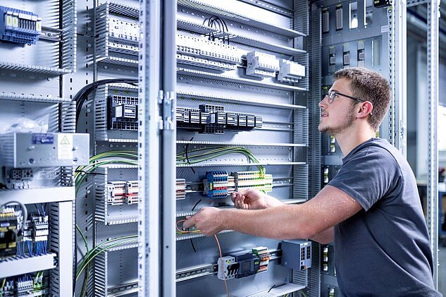 Electronics Technician Apprentice is pulling cables in a controls cabinet