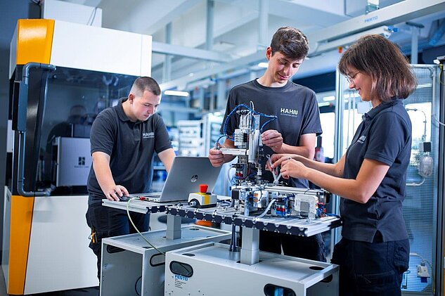 Three apprentices working together on a pneumatic station