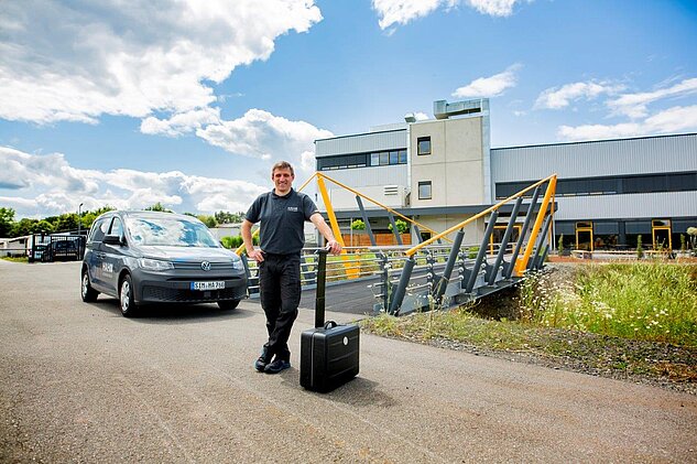 Service Technician in front of the buidling with his equipment and car